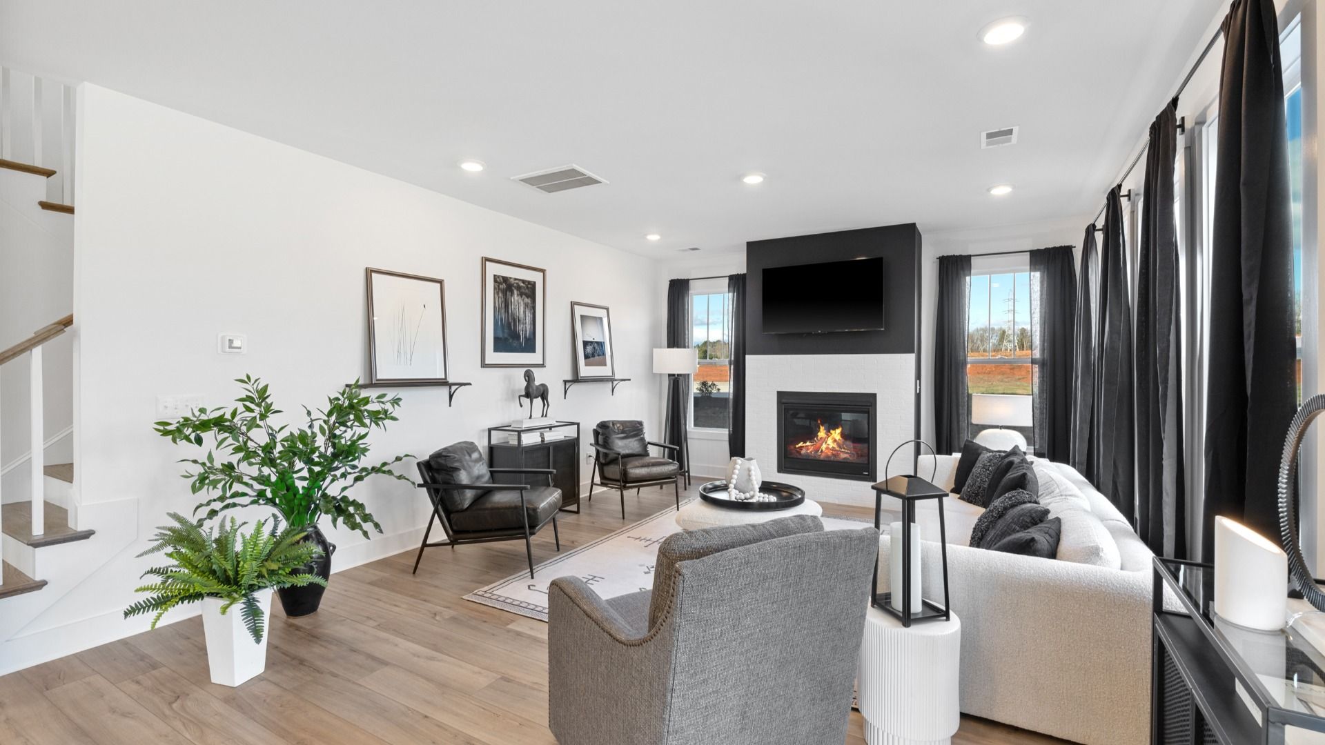 Modern, window adorned family room with fireplace at Mulberry Estates by DRB Homes in Simpsonville, South Carolina