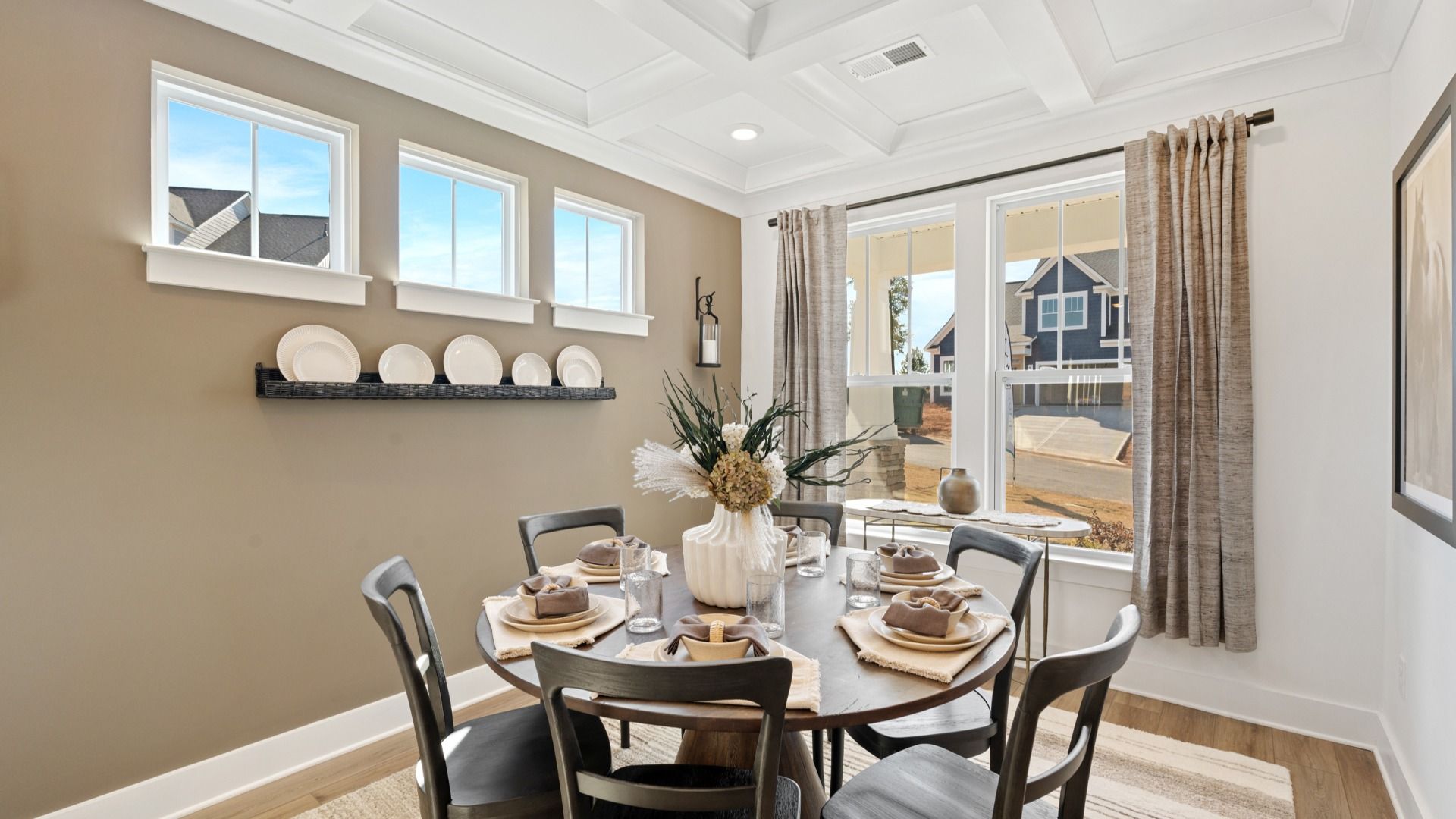 Dining room with multiple windows, elegant, coffered ceiling, and gorgeous hardwood floors at Pleasant Falls by DRB Homes