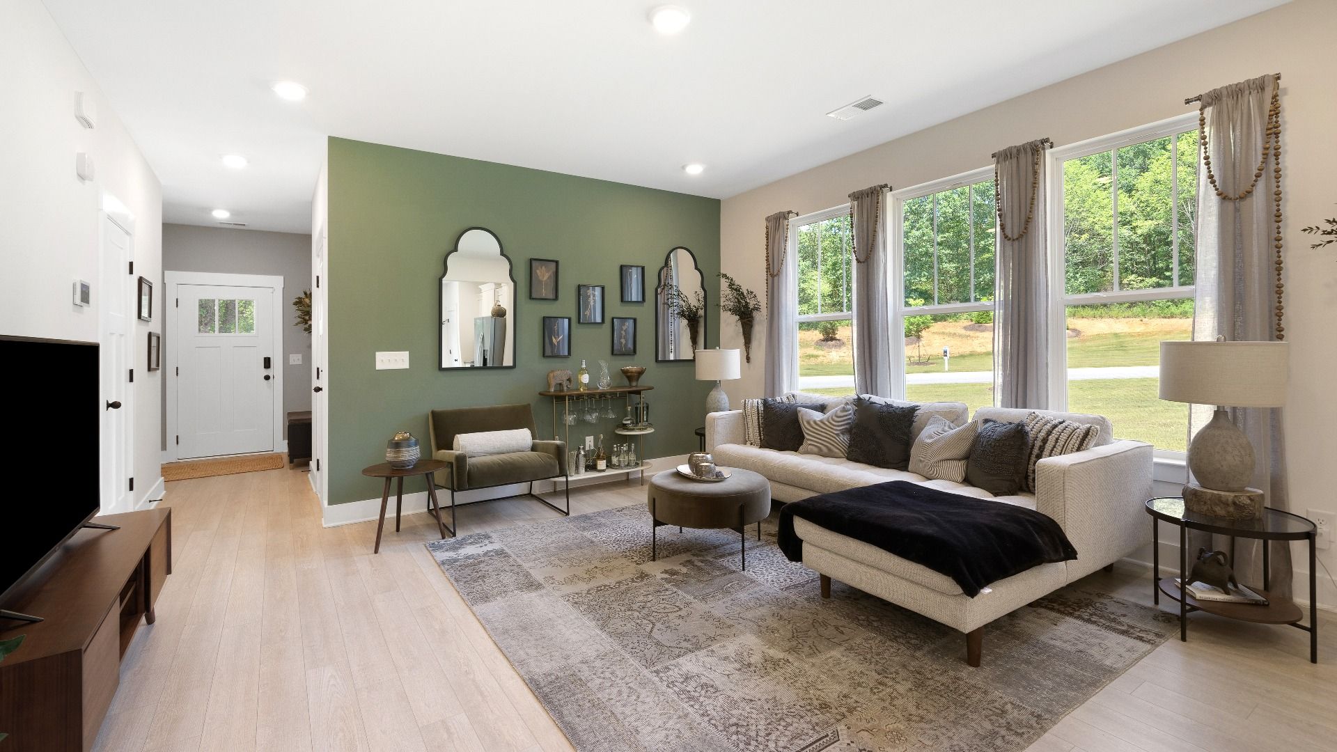 Inviting family room with large windows and hardwood flooring in two story townhome at Tyger Ridge by DRB Homes