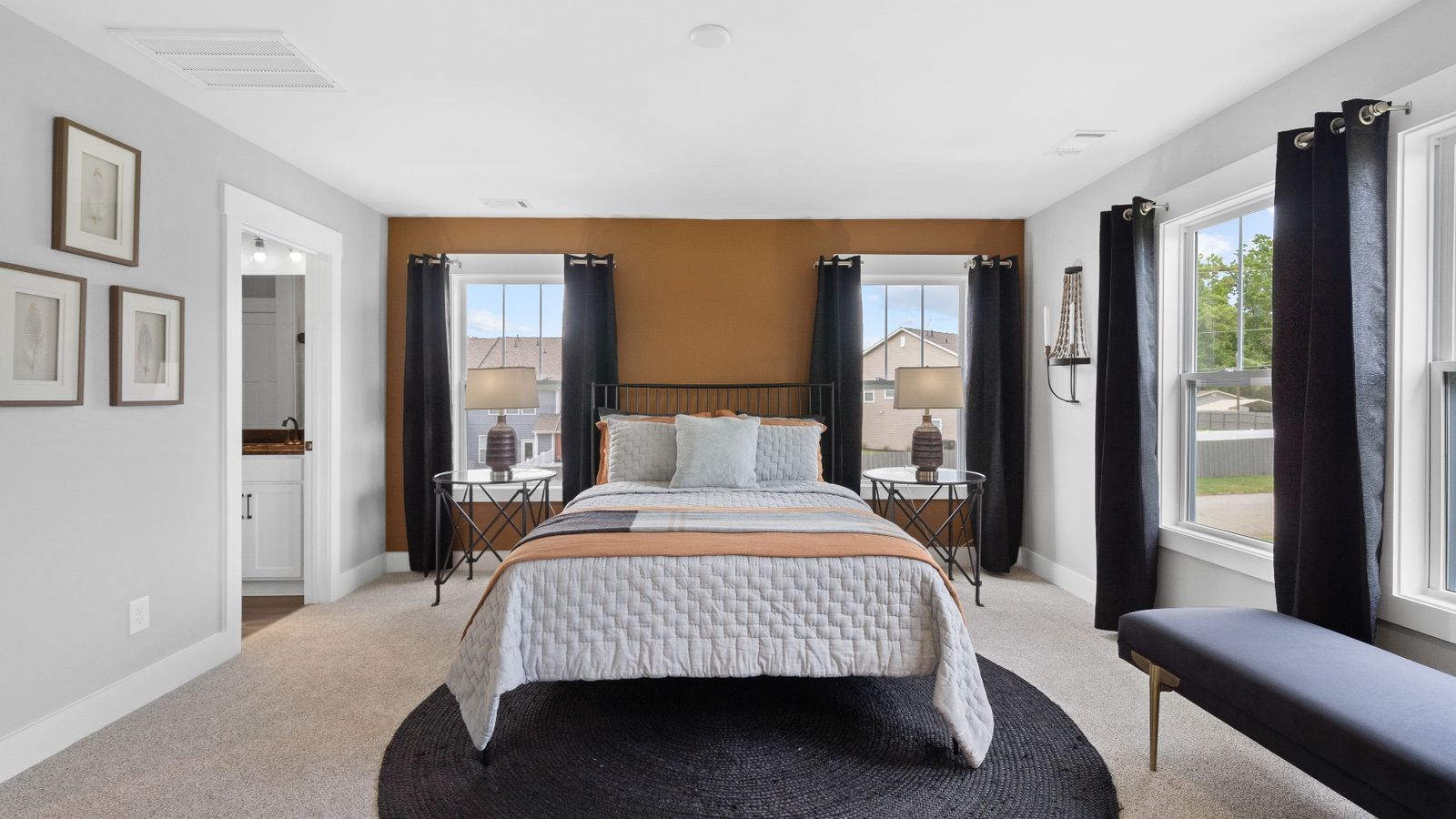 Spacious primary suite with modern decor, large windows, and plush carpet in two story townhome at Tyger Ridge