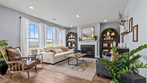 Inviting family room with hardwood flooring, fireplace, and large bay windows at Woodglen by DRB Homes