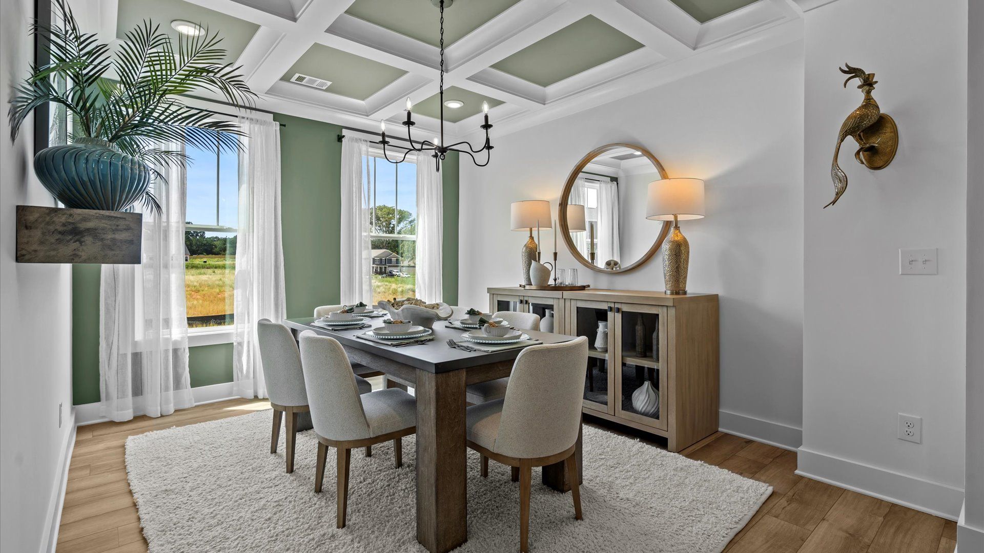 Cozy dining room with green accented coffered ceilings, modern chandelier, and large windows in Piedmont, SC