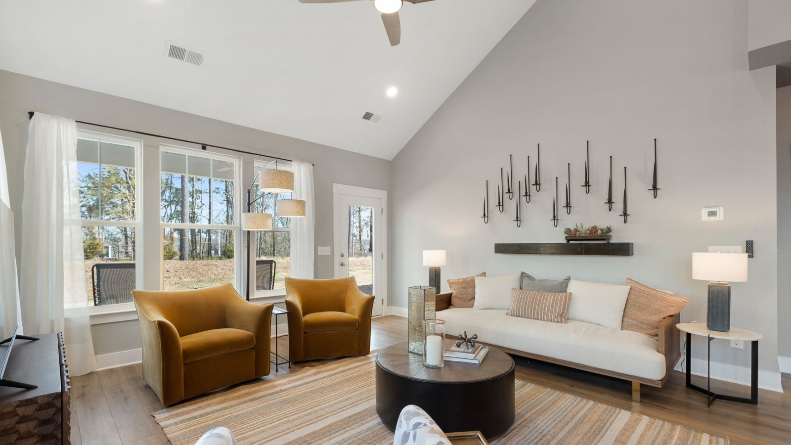 Family room with modern decor, gray walls, large windows and two story ceiling at Village at Midway by DRB Homes in Anderson