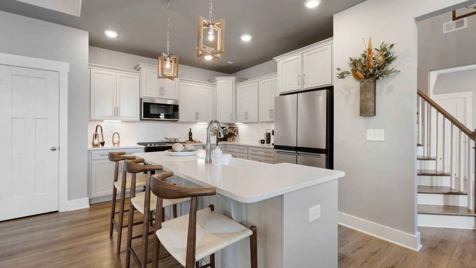 Kitchen featuring white quartz countertops, crown molding, modern furniture, and LVP at Village at Midway by DRB Homes