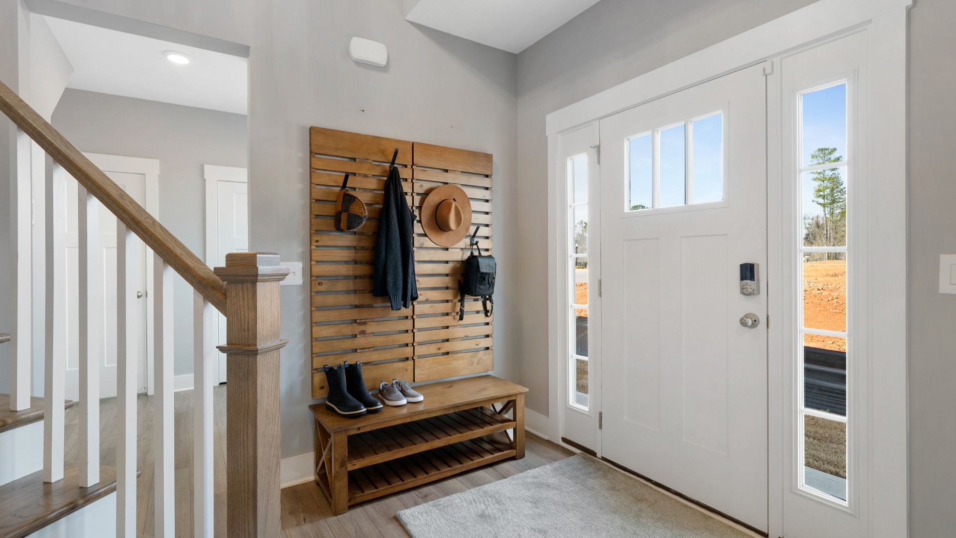 Entry with two story ceiling, oak stairs, open railing, mudroom, and LVP flooring at Village at Midway by DRB Homes