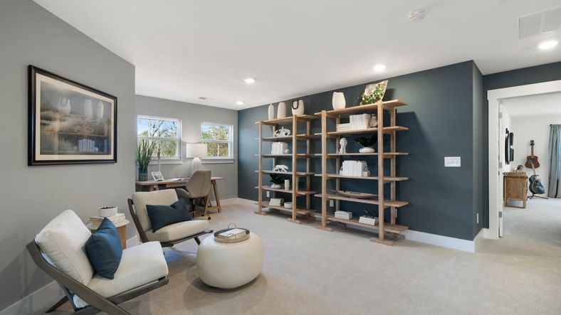 Loft space in Anderson, SC with accent wall, large windows, and plush carpet at Village at Midway by DRB Homes