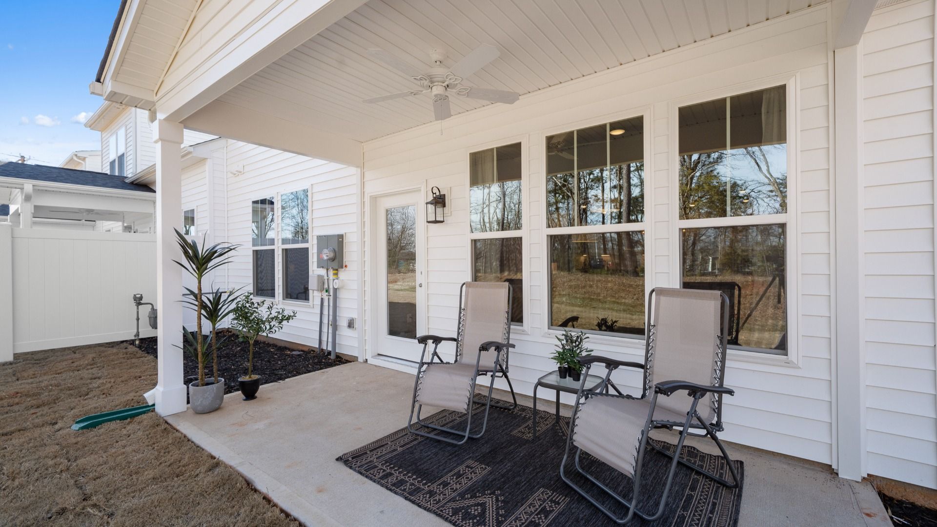 White exterior home with covered back porch with ceiling fan and patio furniture in Anderson, SC at Village at Midway