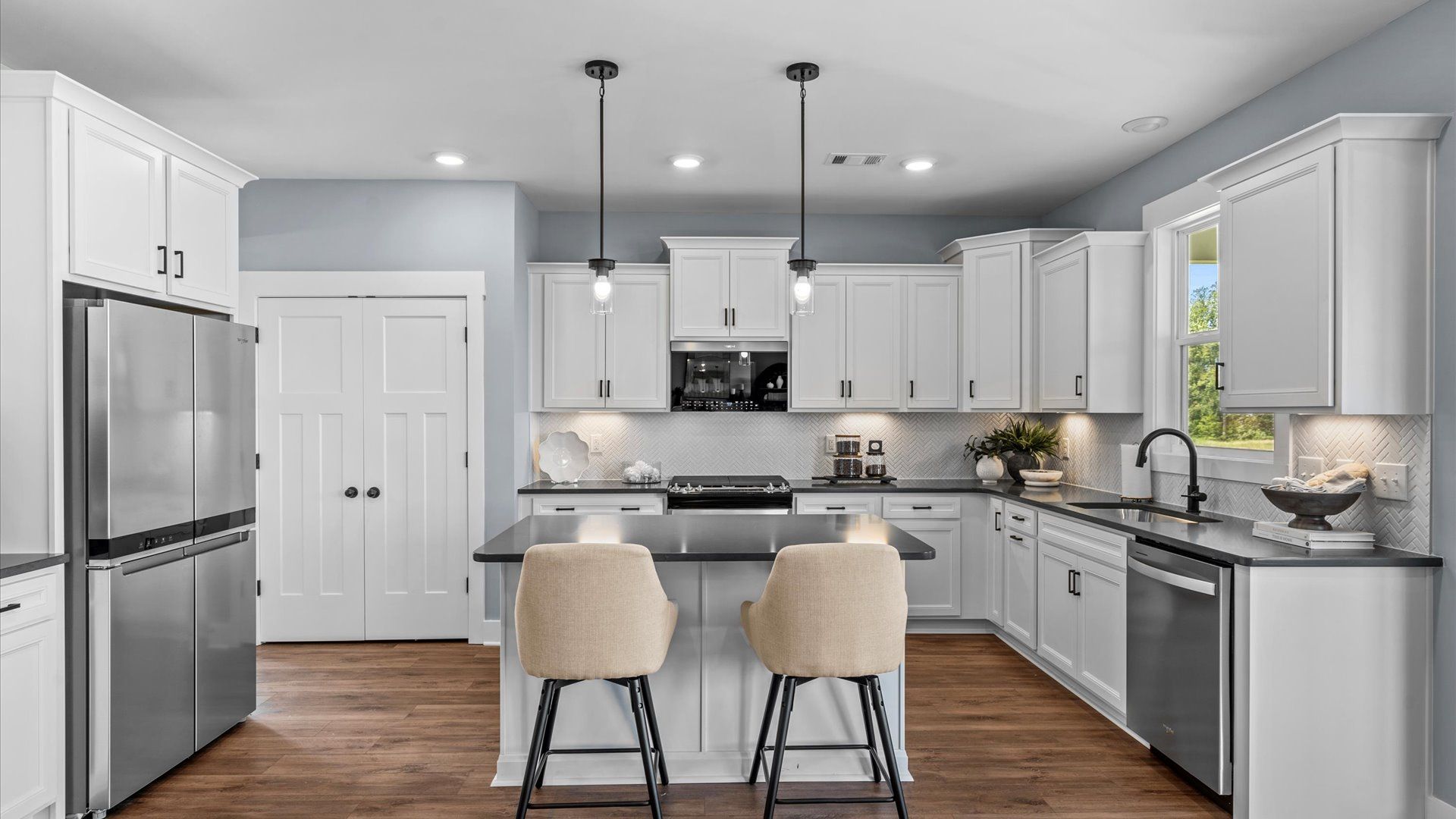 Beautiful white cabinetry kitchen with modern black accents and pendant lighting in two story home at DRB Homes in Easley, SC