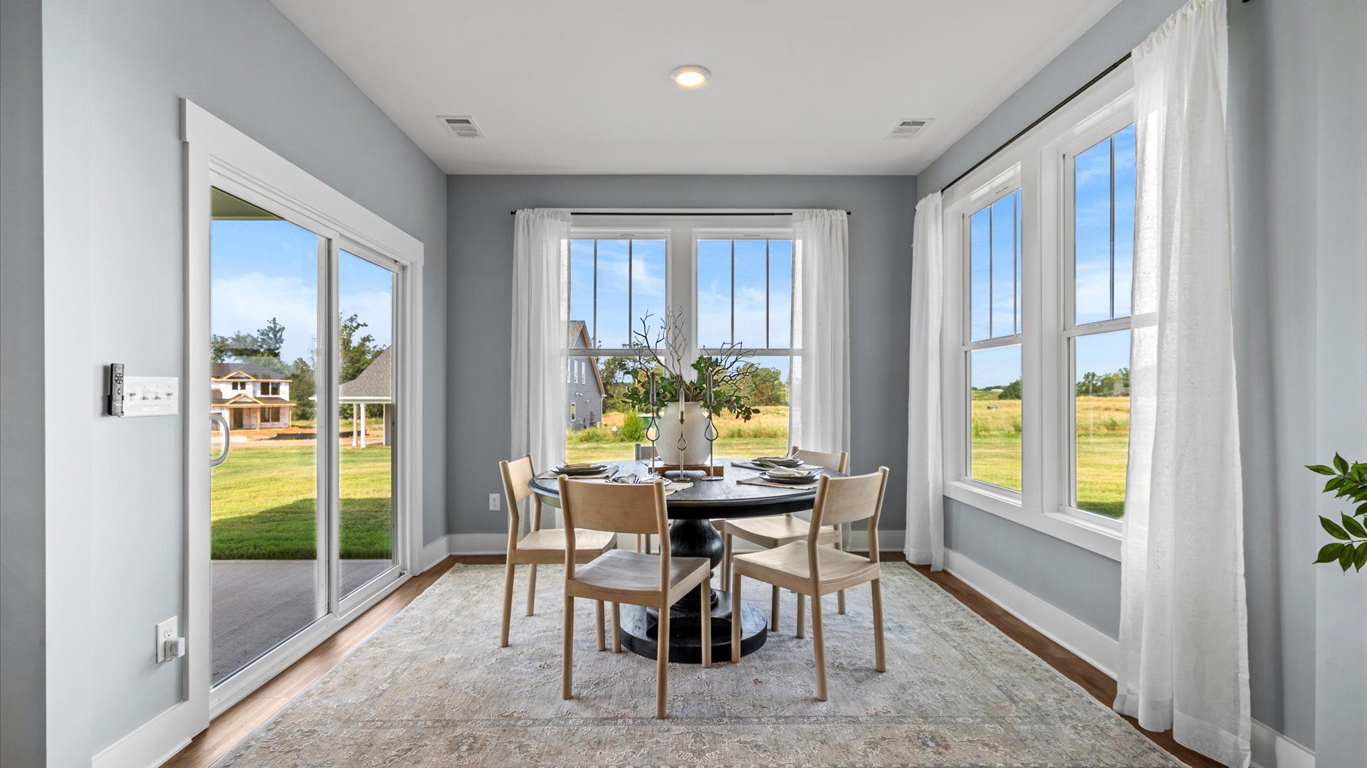 Window adorned extended breakfast area with gray walls and outdoor access in two story home at DRB Homes in Easley, SC