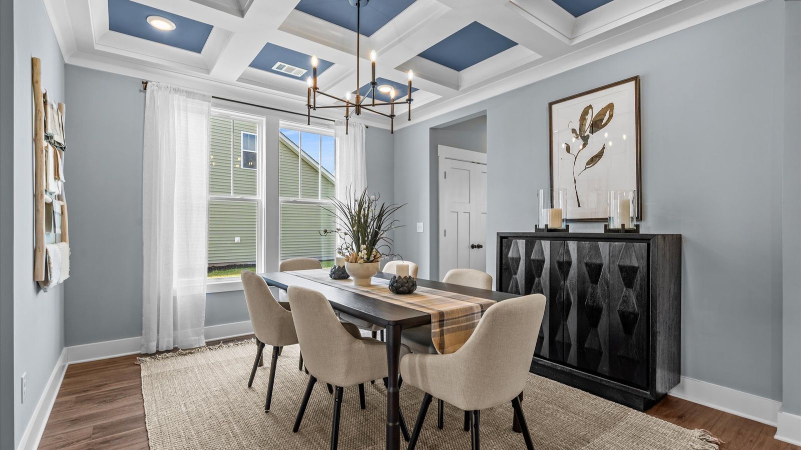 Cozy dining room with coffered ceilings, modern chandelier, and large windows in two story home at DRB Homes in Easley, SC