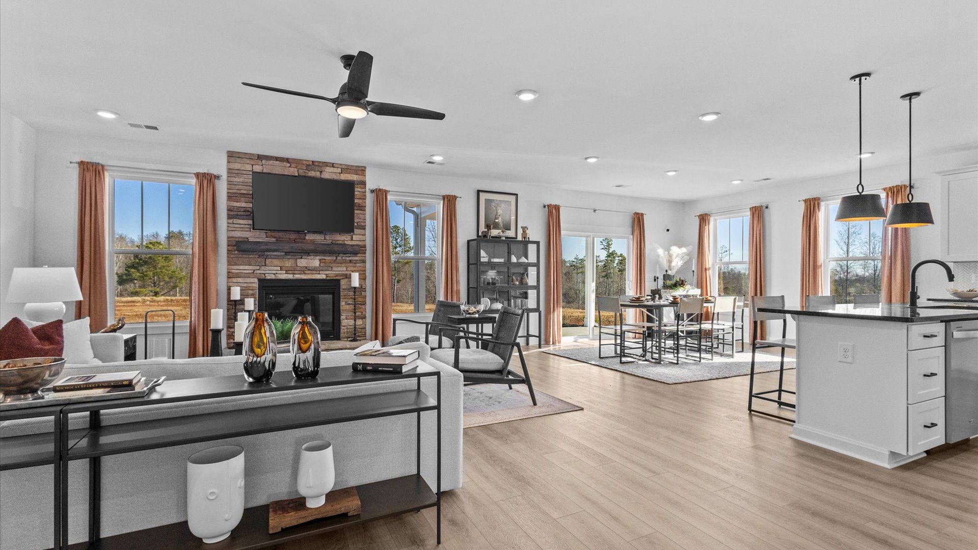 Open concept downstairs with hardwood flooring, elevated ceilings & gorgeous stone fireplace at Wells Crossing by DRB Homes