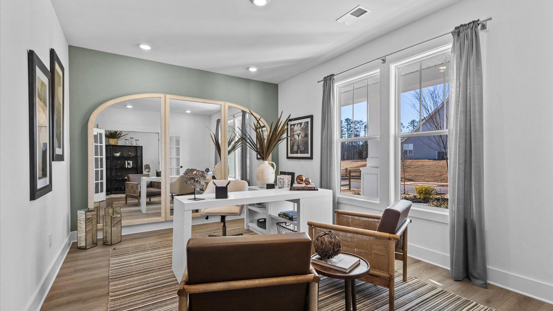 Natural decor study with hardwood flooring, large windows, and elevated ceilings at Wells Crossing by DRB Homes