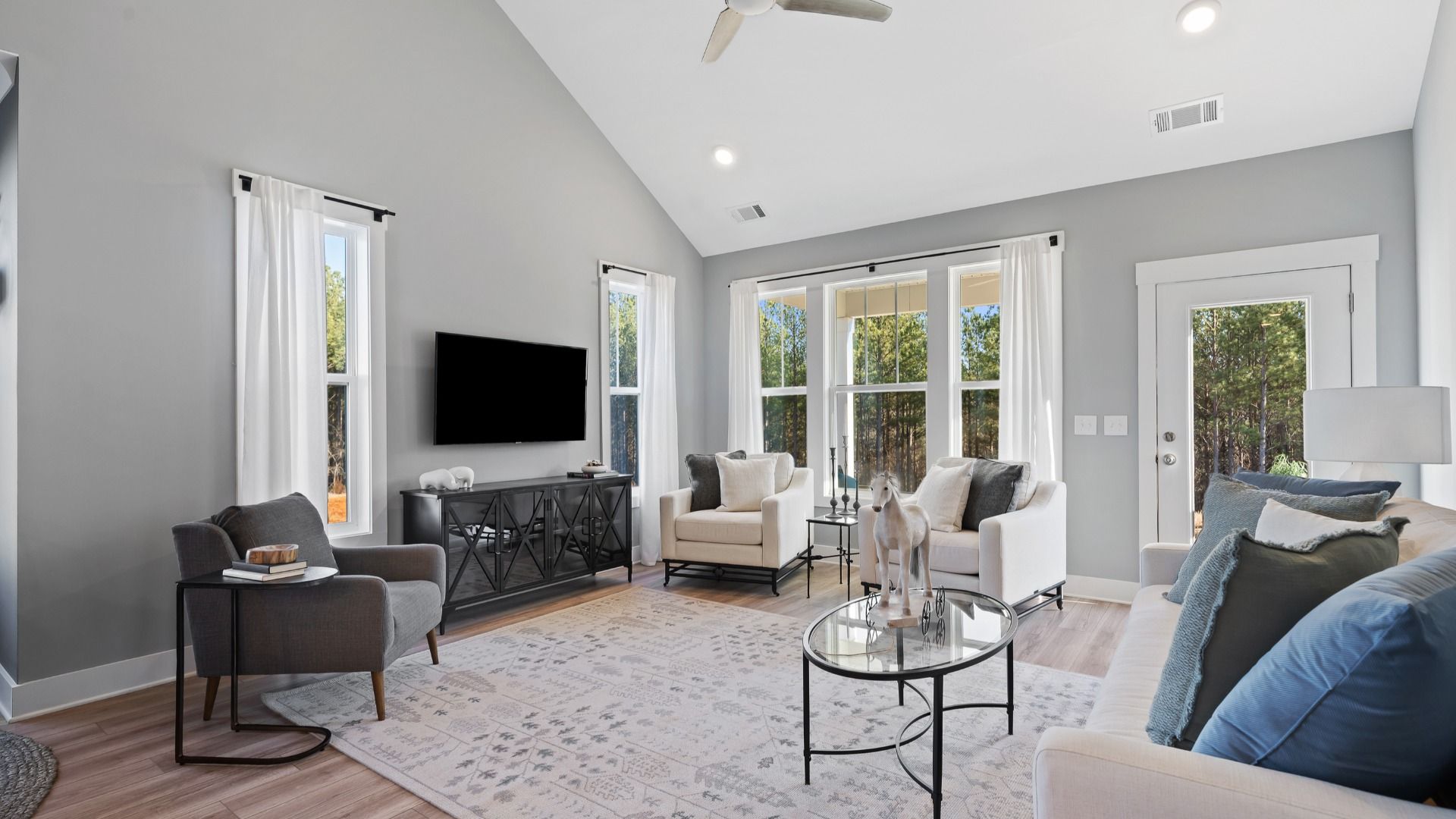 Two story family room with trendy decor, large windows and yard access in Anderson, SC at Village at Midway by DRB Homes