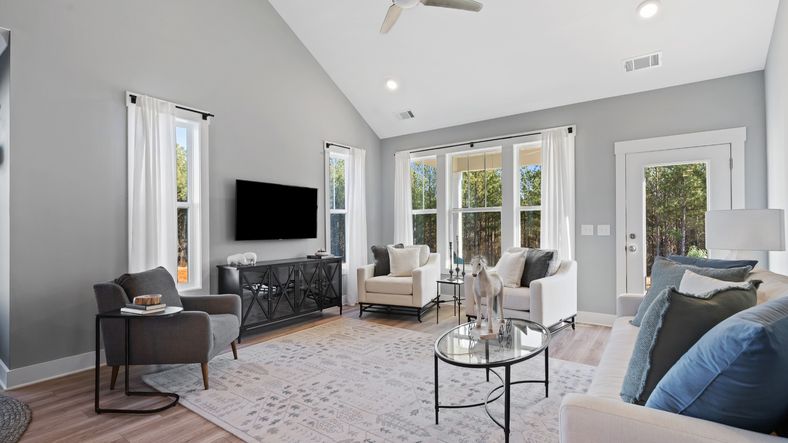 Two story family room with trendy decor, large windows and yard access in Anderson, SC at Village at Midway by DRB Homes