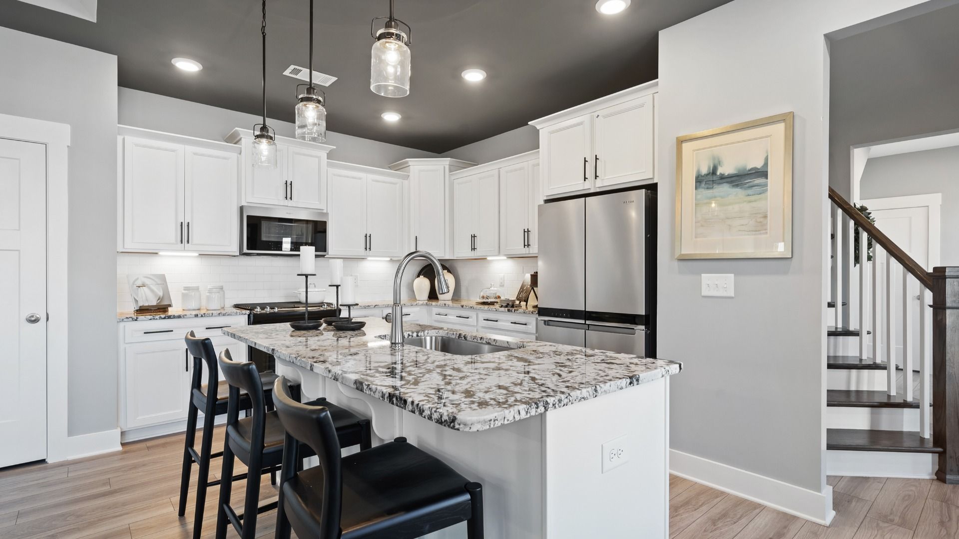 Kitchen at Village at Midway by DRB Homes with modern accents, dark ceiling, granite countertops, and white cabinetry