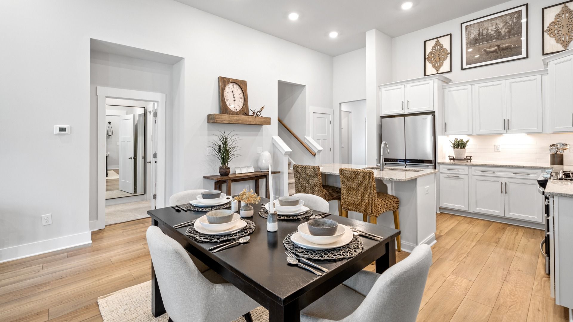 Large kitchen with breakfast table, hardwood flooring, white cabinetry, and large island with room for counterstools