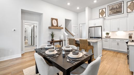 Large kitchen with breakfast table, hardwood flooring, white cabinetry, and large island with room for counterstools