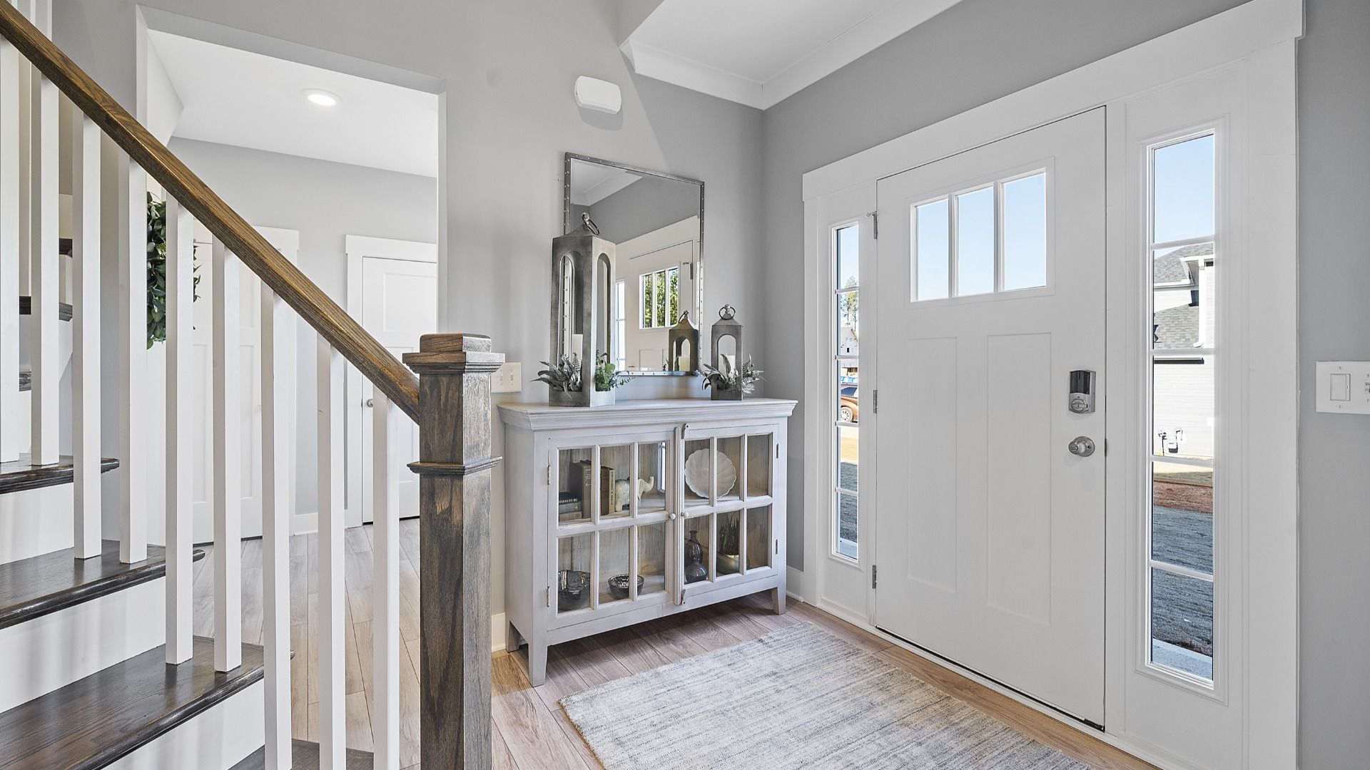 Two story entry with oak stairs, open railing, LVP flooring, lots of windows, and farm house decor at Village at Midway