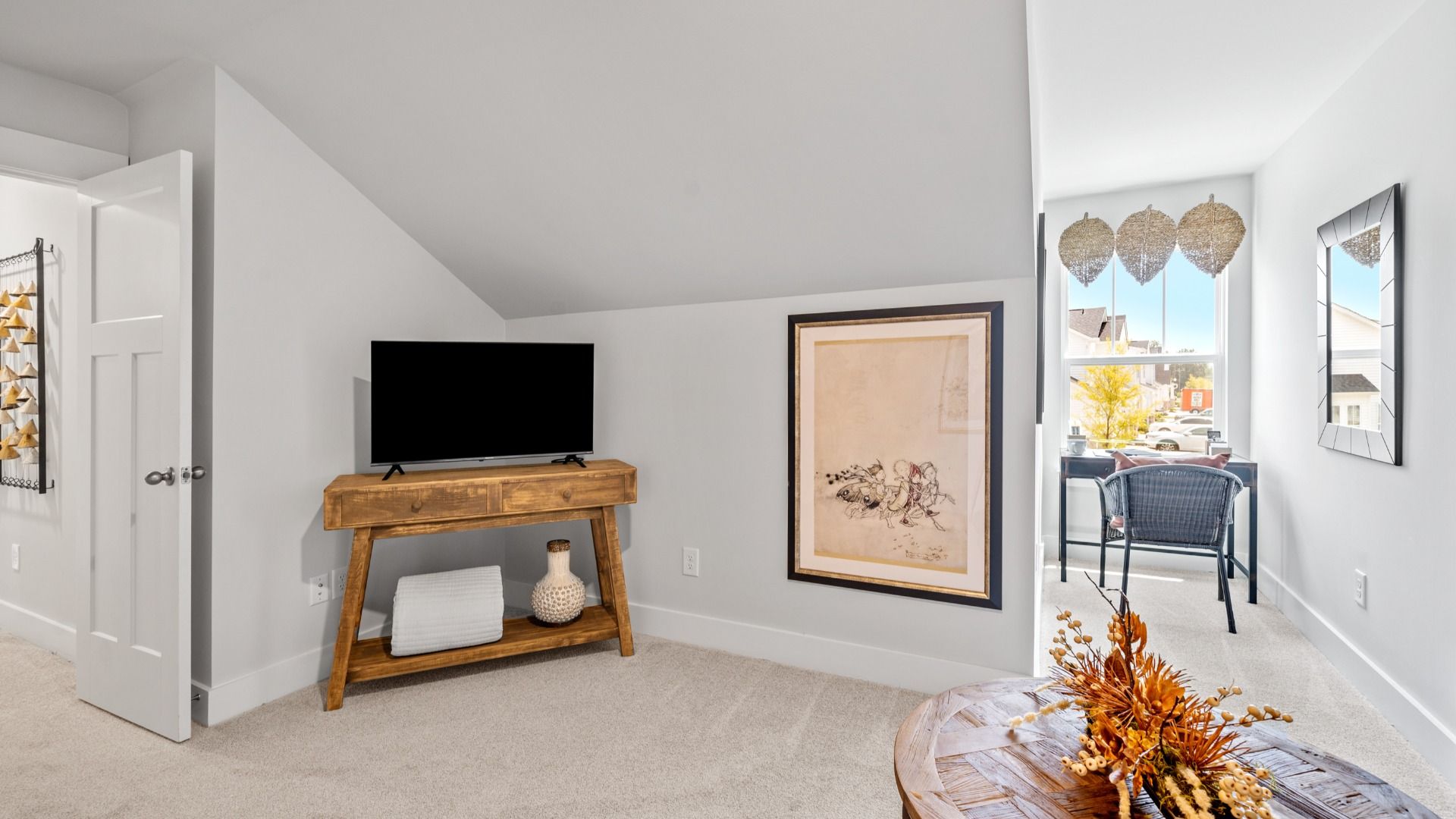 Cozy carpeted loft space with gray walls and large window at Aspen Ridge by DRB Homes in Lyman, SC