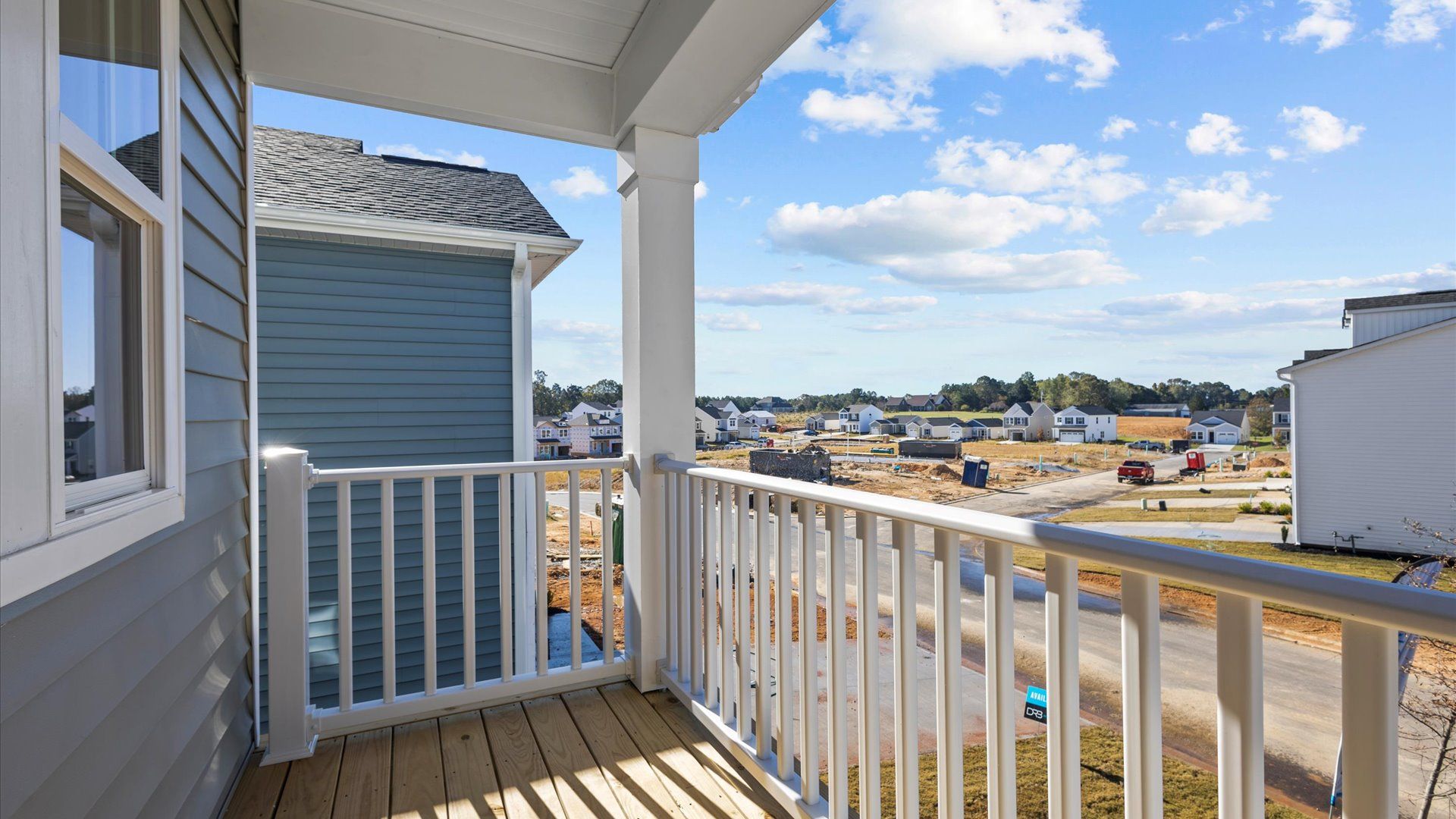 Spacious second story porch with white railing and plenty of room for patio furniture at Pleasant Falls by DRB Homes