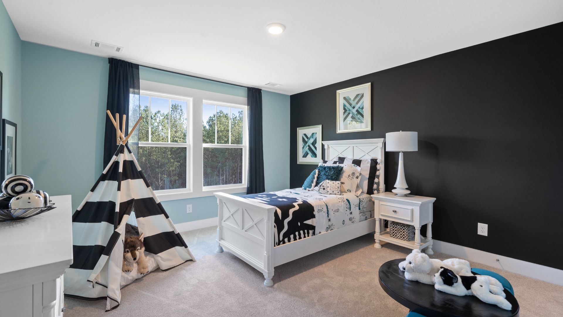 Cozy child's bedroom with accent walls, plush carpet, and large windows in the Lakehurst plan by DRB Homes
