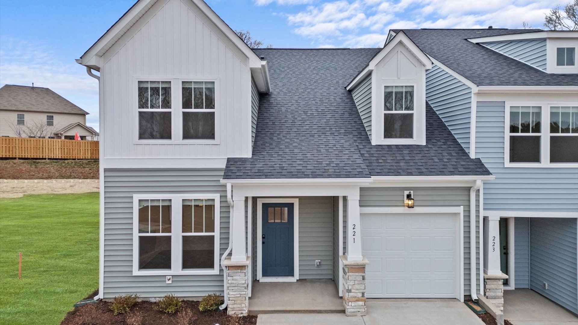 Grey and white siding end unit with dark blue door, two car driveway with one car garage, and stone detail in Lyman, SC