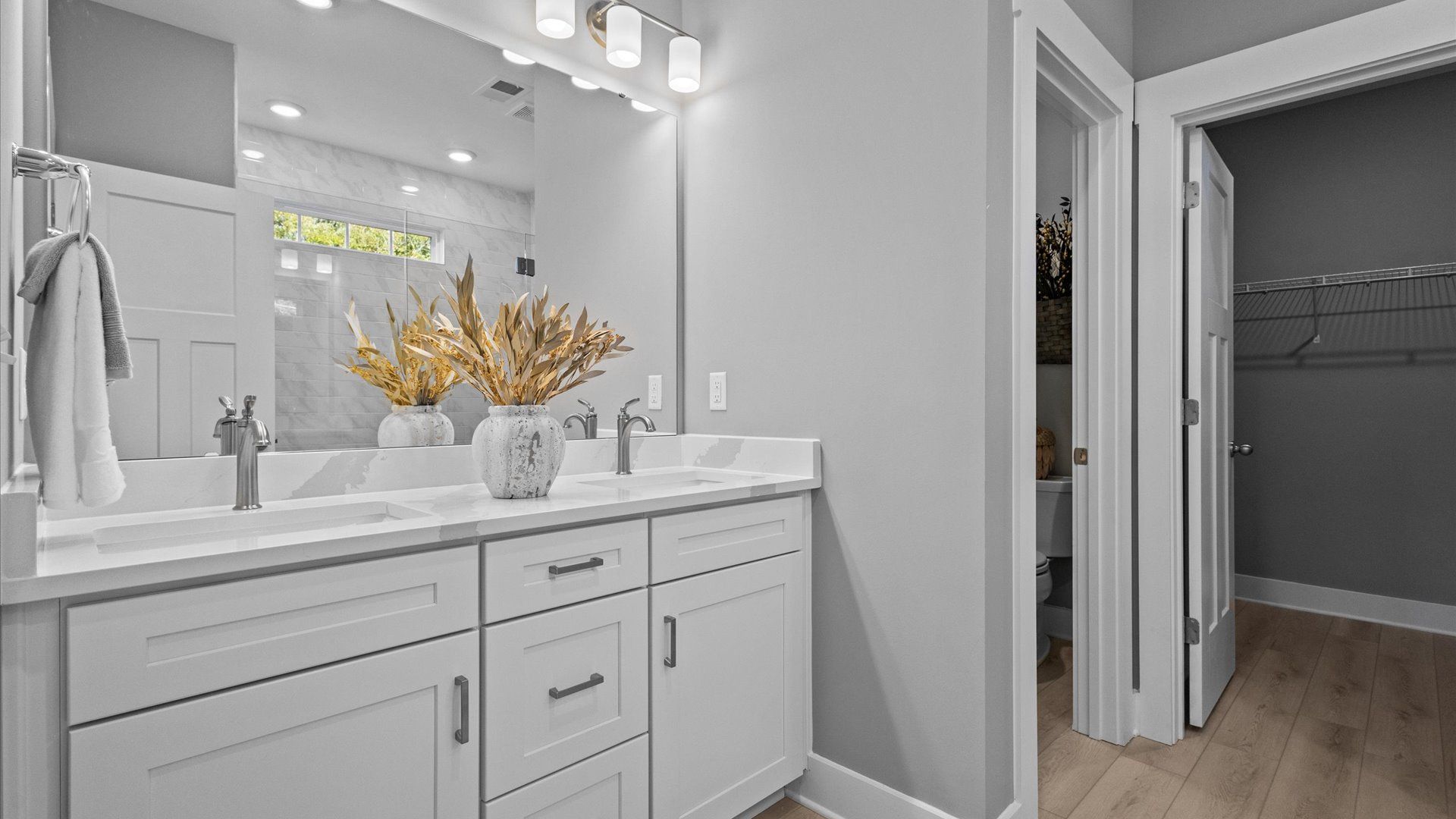 Marble countertop double sink vanity with gray and white details and hardwood flooring at Pleasant Falls by DRB Homes