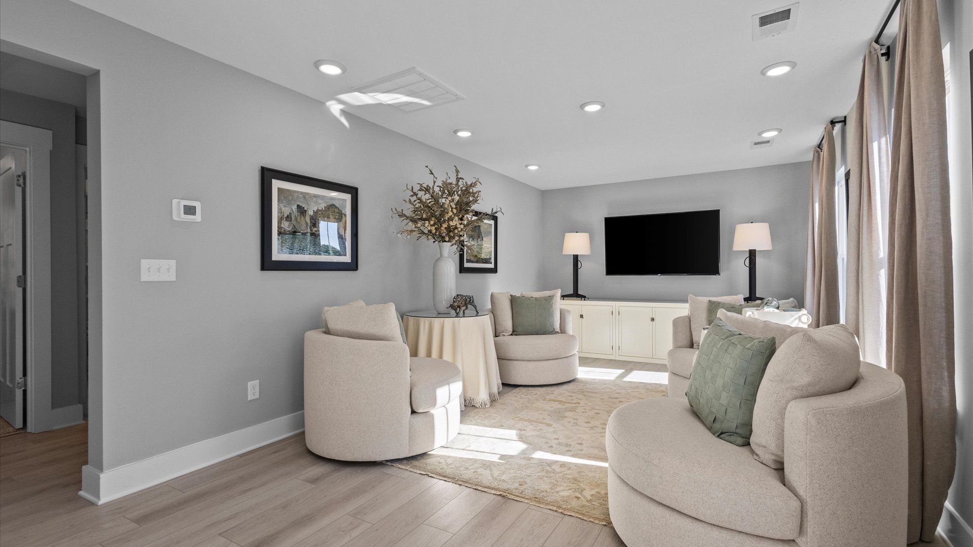 Loft space with large windows, gray walls, and hardwood flooring with tall ceilings at Pleasant Falls by DRB Homes