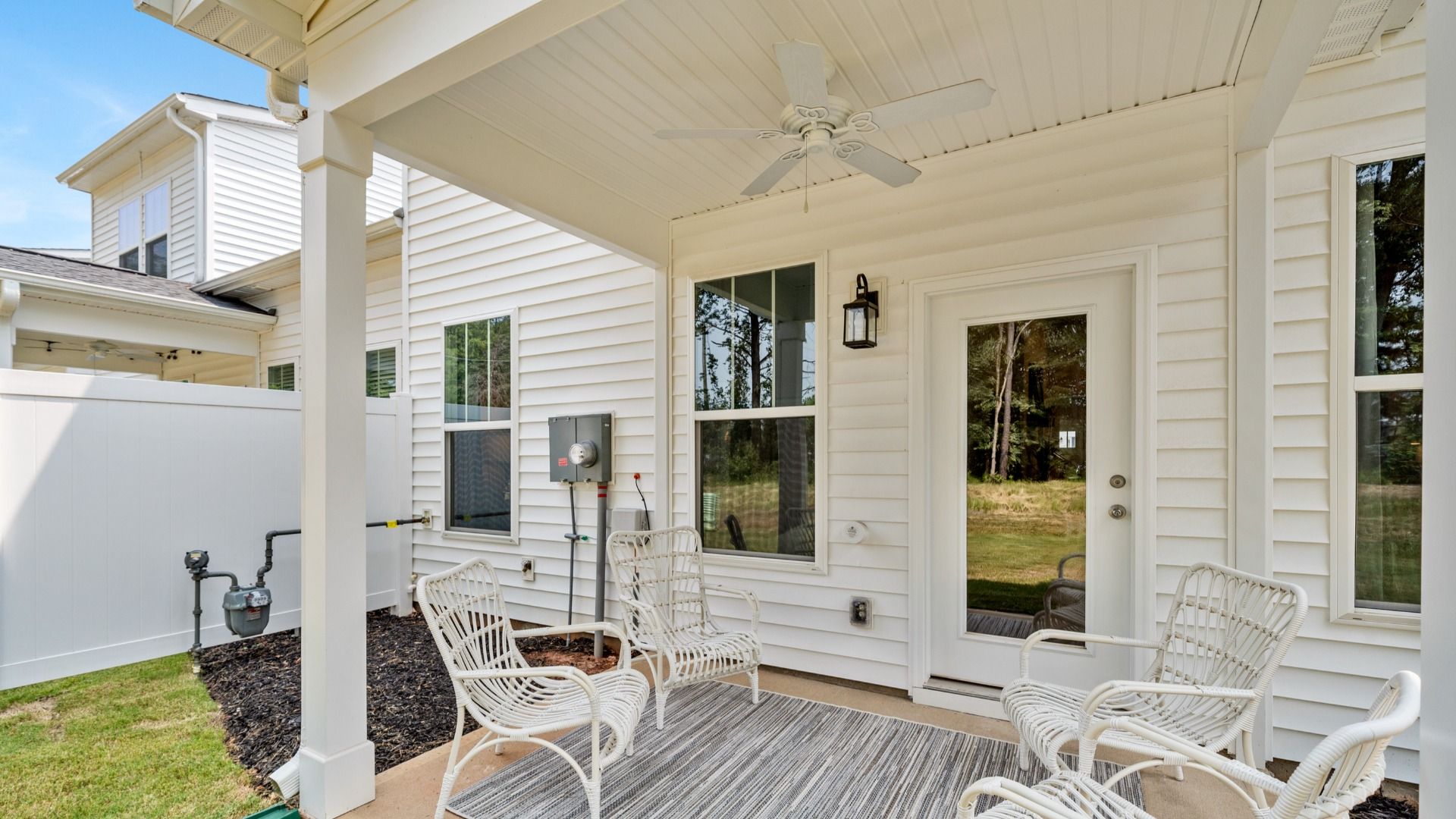 Covered porch on white exterior home with ceiling fan, lantern, and backyard access in Lyman, SC