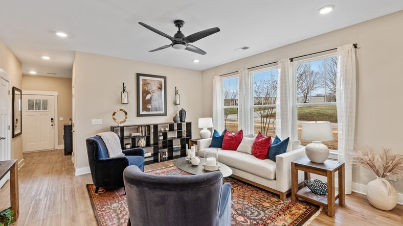 Cozy family room with ceiling fan and large windows in two story townhome at Saluda Crossing by DRB Homes in Piedmont, SC
