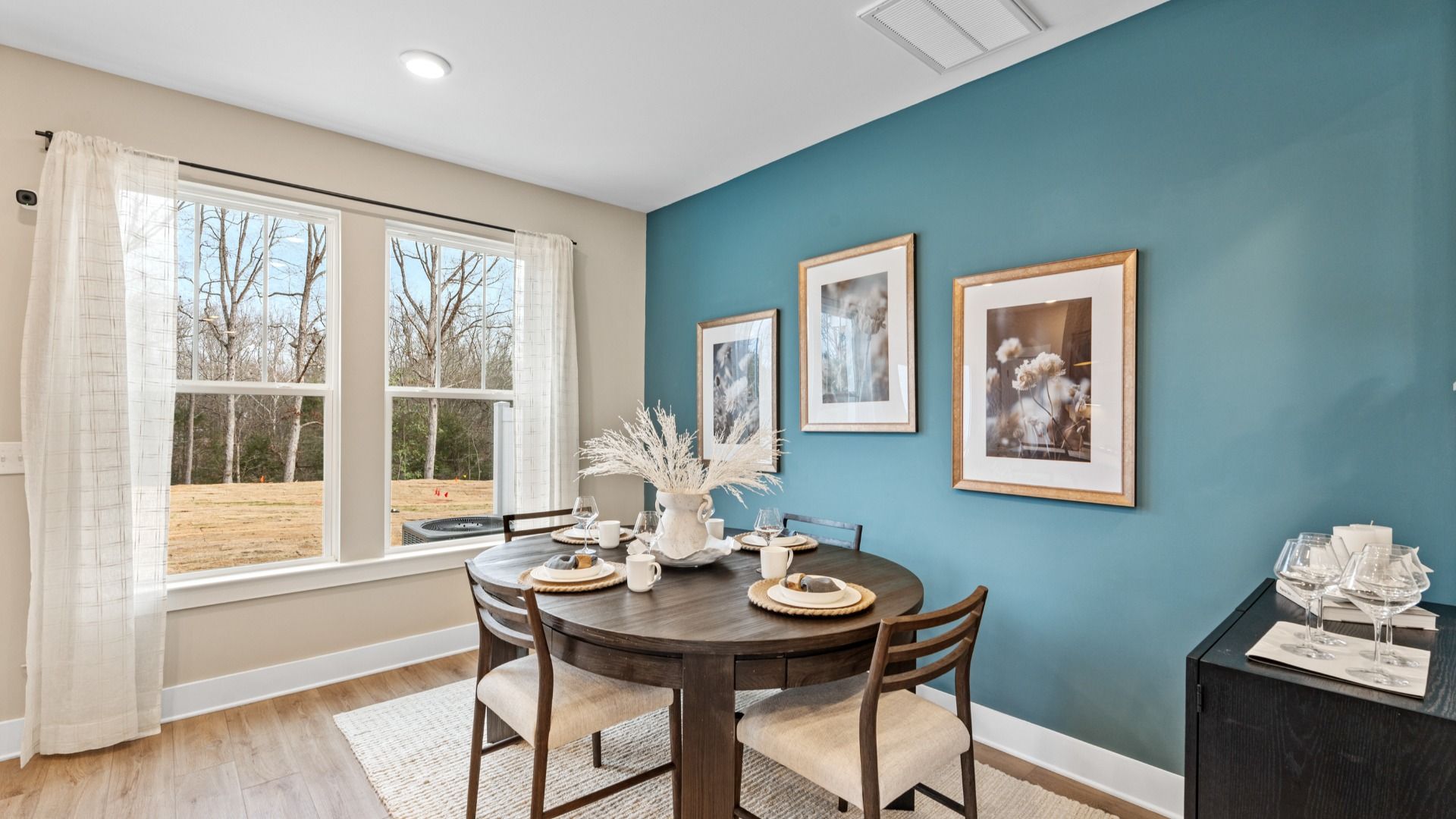Breakfast area with large windows and teal accent wall in two story townhome at Saluda Crossing by DRB Homes in Piedmont, SC