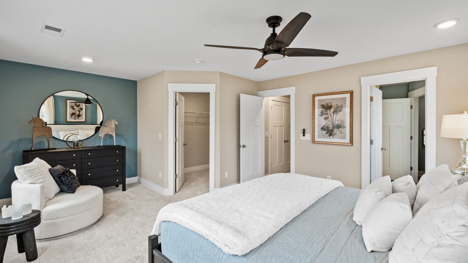 Plush carpeted primary suite with accent wall and ceiling fan in two story townhome at Saluda Crossing by DRB Homes