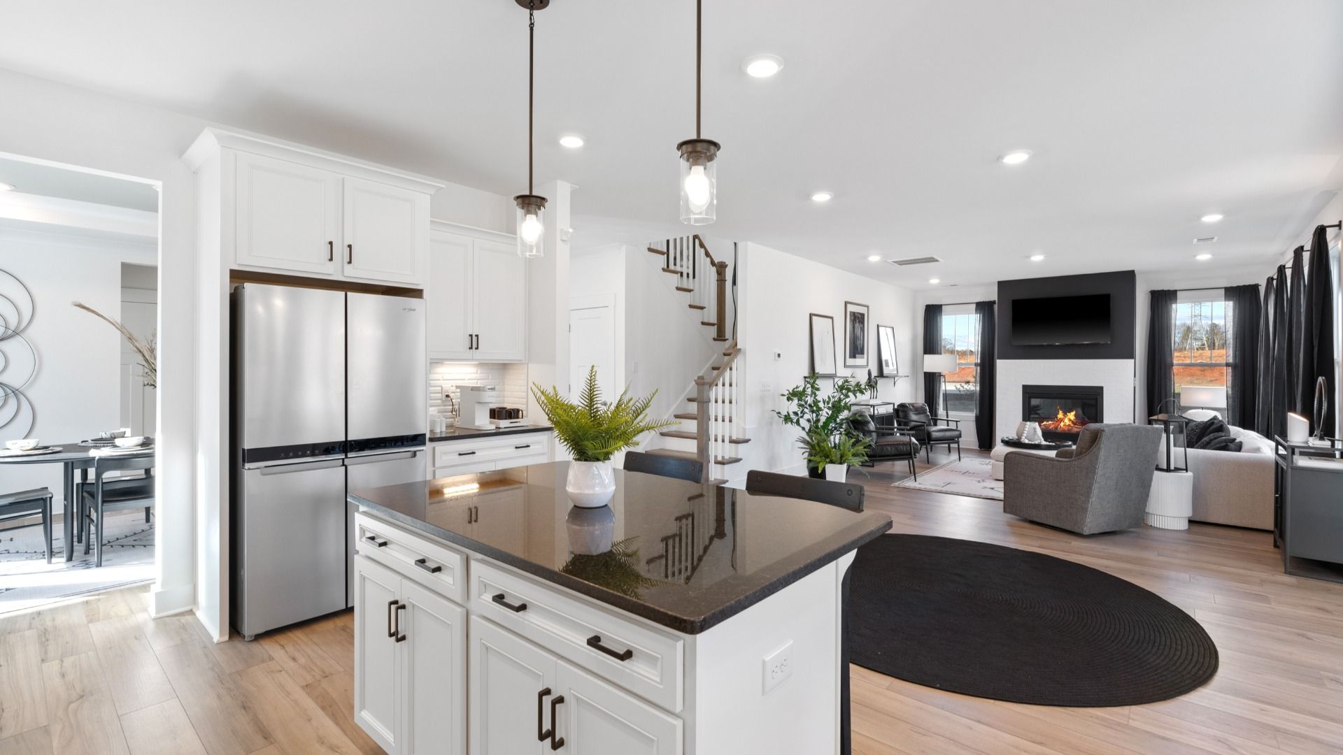 Modern black and white kitchen with white cabinetry, hardwood flooring, and tall ceilings at Fox Hollow by DRB Homes