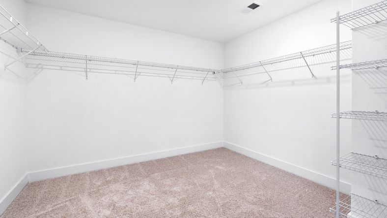 Large walk-in closet in primary suite with included shelving, hanging room, and carpeted flooring at Fox Hollow by DRB Homes