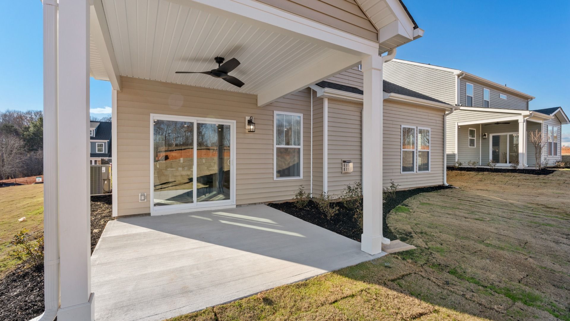 Covered back patio with ceiling fan and access to large backyard and sliding glass door at Fox Hollow by DRB Homes