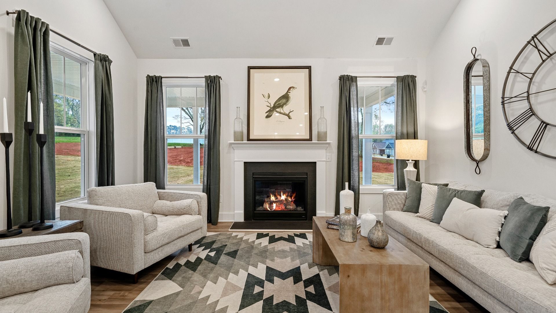 Green accented, inviting family room with large windows, vaulted ceilings, and fireplace at Pinebrook by DRB Homes