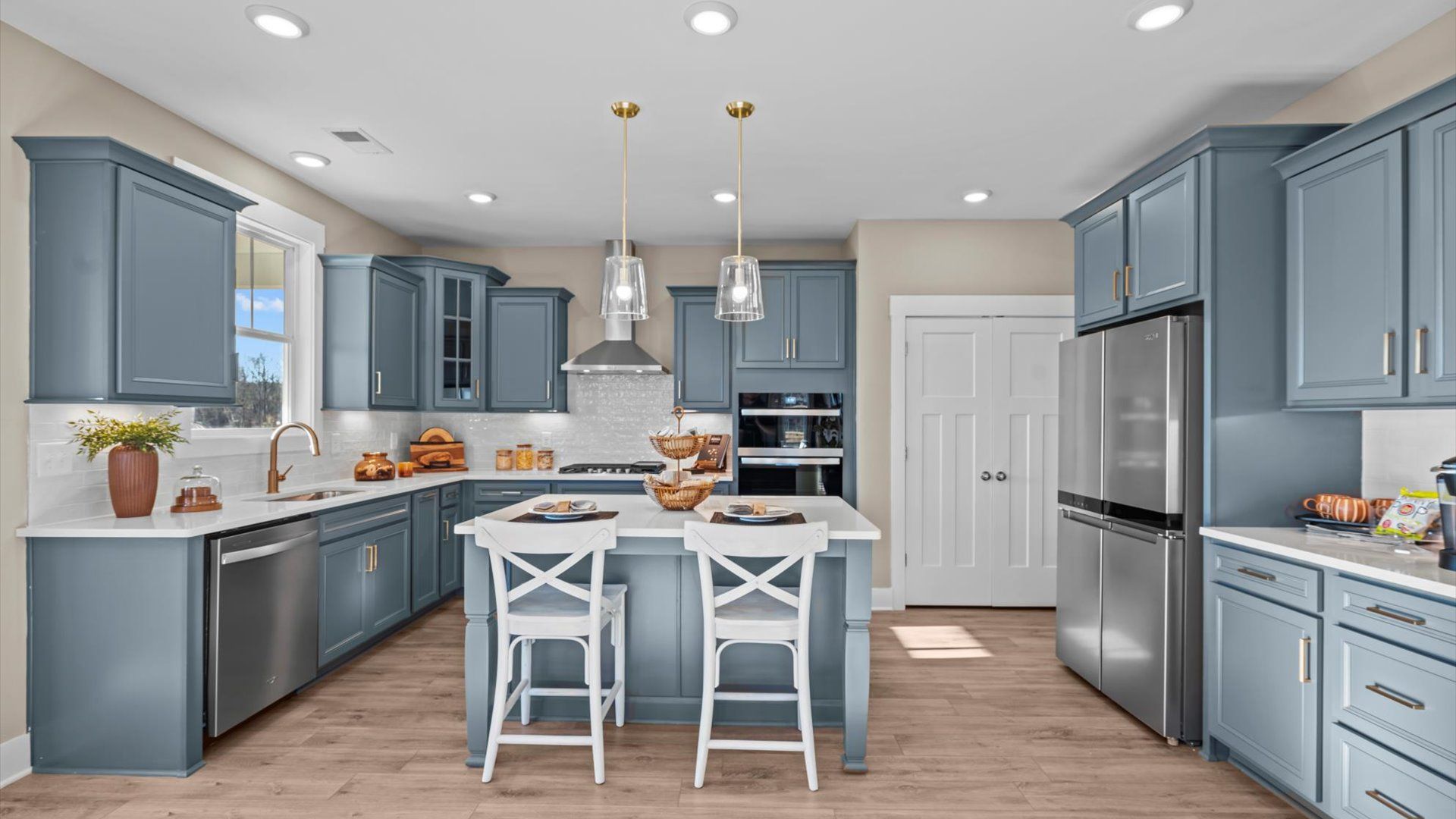 Stunning blue cabinetry kitchen with hardwood flooring, pendant lighting, and kitchen island at Creeks at Midway