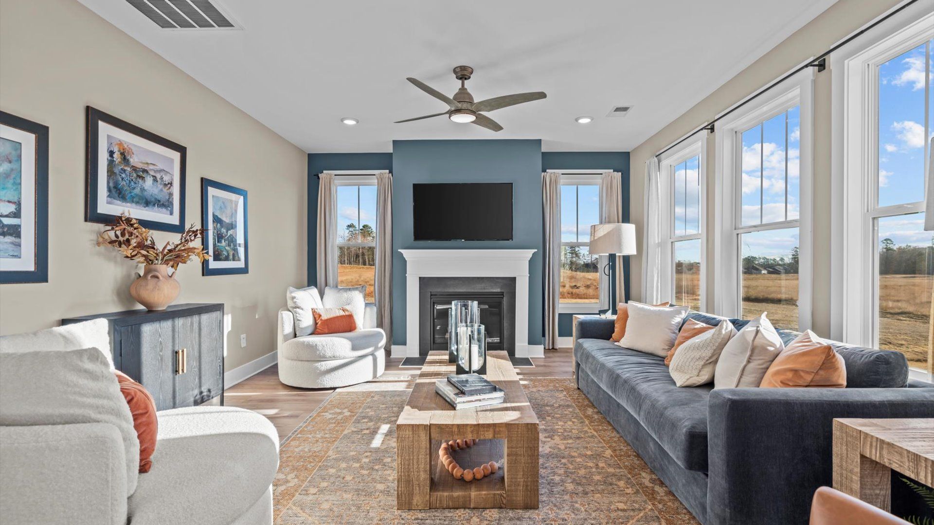 DRB Homes' Magnolia Park open concept family room with hardwood flooring, large windows, fireplace, and ceiling fan