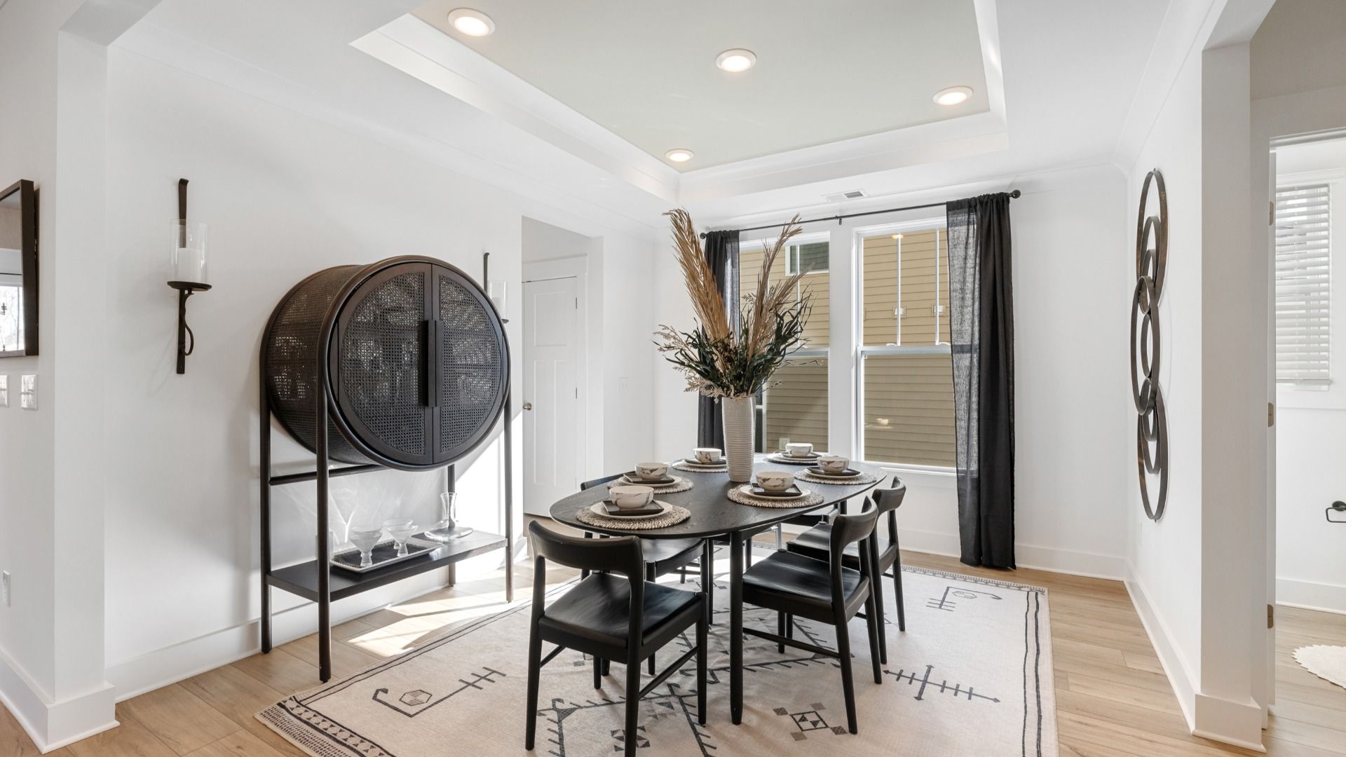 Black and white modern dining room with hardwood flooring and luxury vaulted ceiling detail at Fox Hollow by DRB Homes