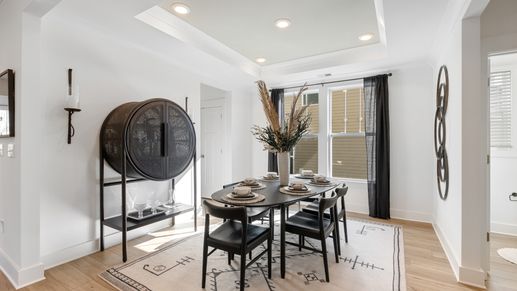 Black and white modern dining room with hardwood flooring and luxury vaulted ceiling detail at Fox Hollow by DRB Homes