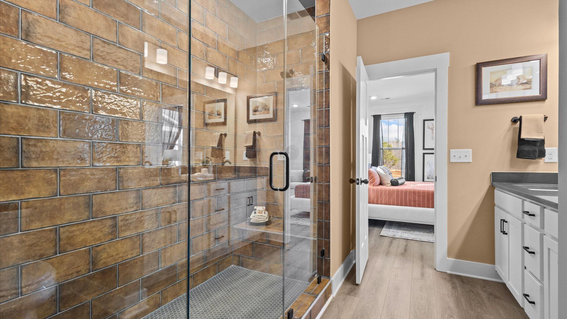 Brand new primary bathroom with warm toned tiled walk-in frameless shower at Wells Crossing by DRB Homes in Seneca, SC