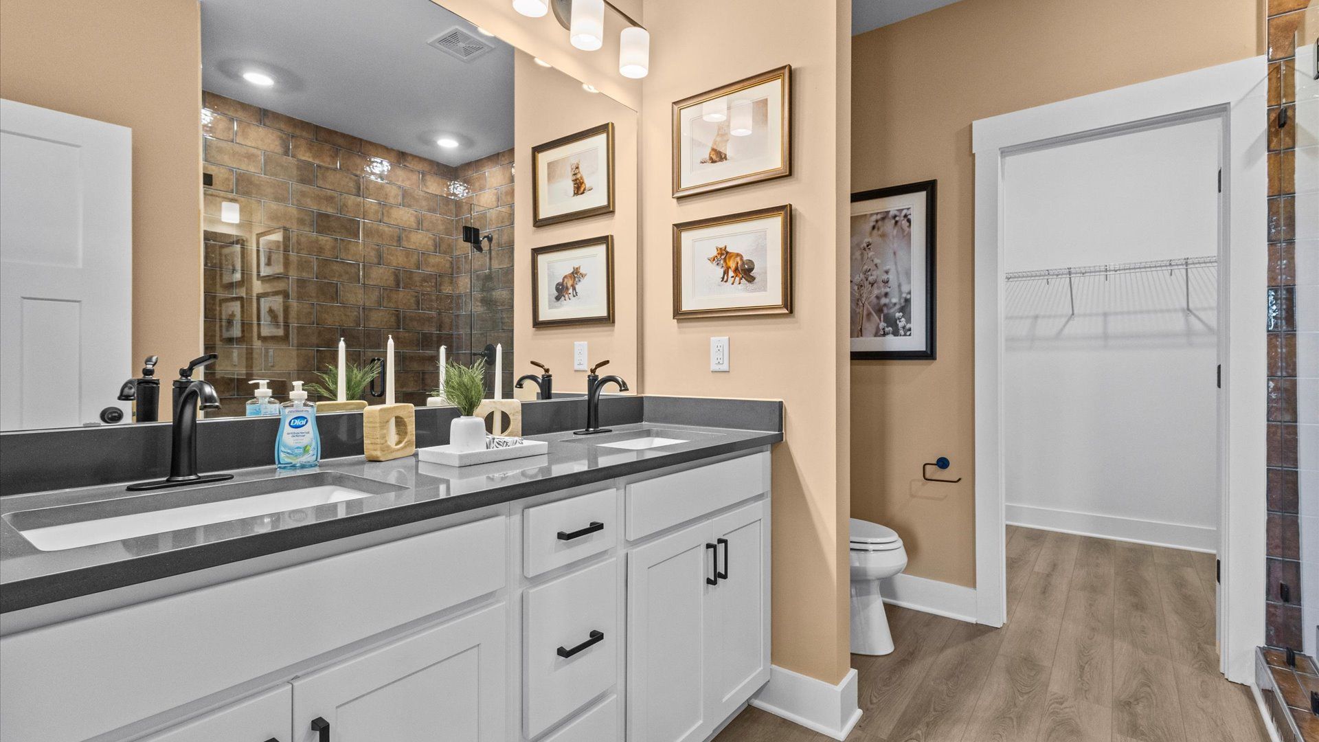 Black accented primary bathroom with granite counter topped double sink vanity at Wells Crossing by DRB Homes in Seneca, SC