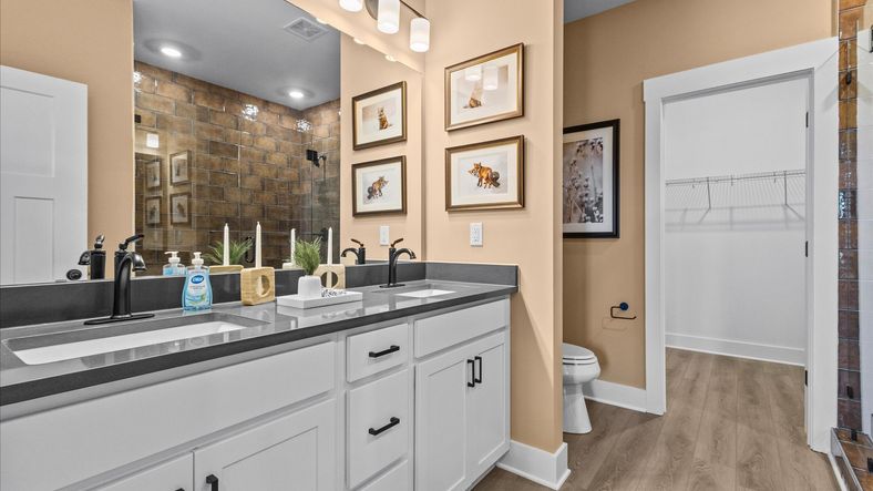 Black accented primary bathroom with granite counter topped double sink vanity at Wells Crossing by DRB Homes in Seneca, SC