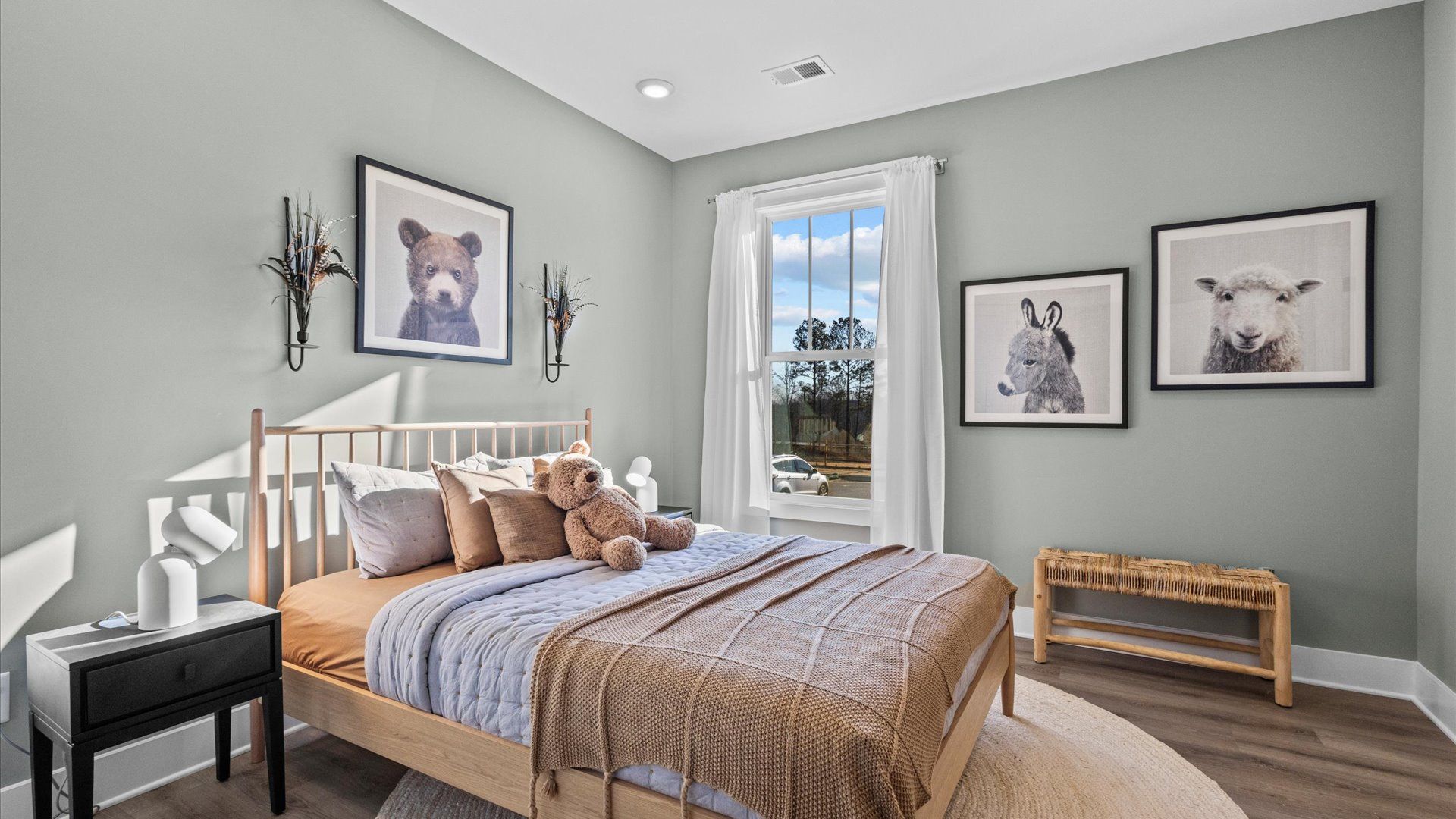 Secondary bedroom decorated for a child with hardwood flooring and large window at Wells Crossing by DRB Homes in Seneca, SC