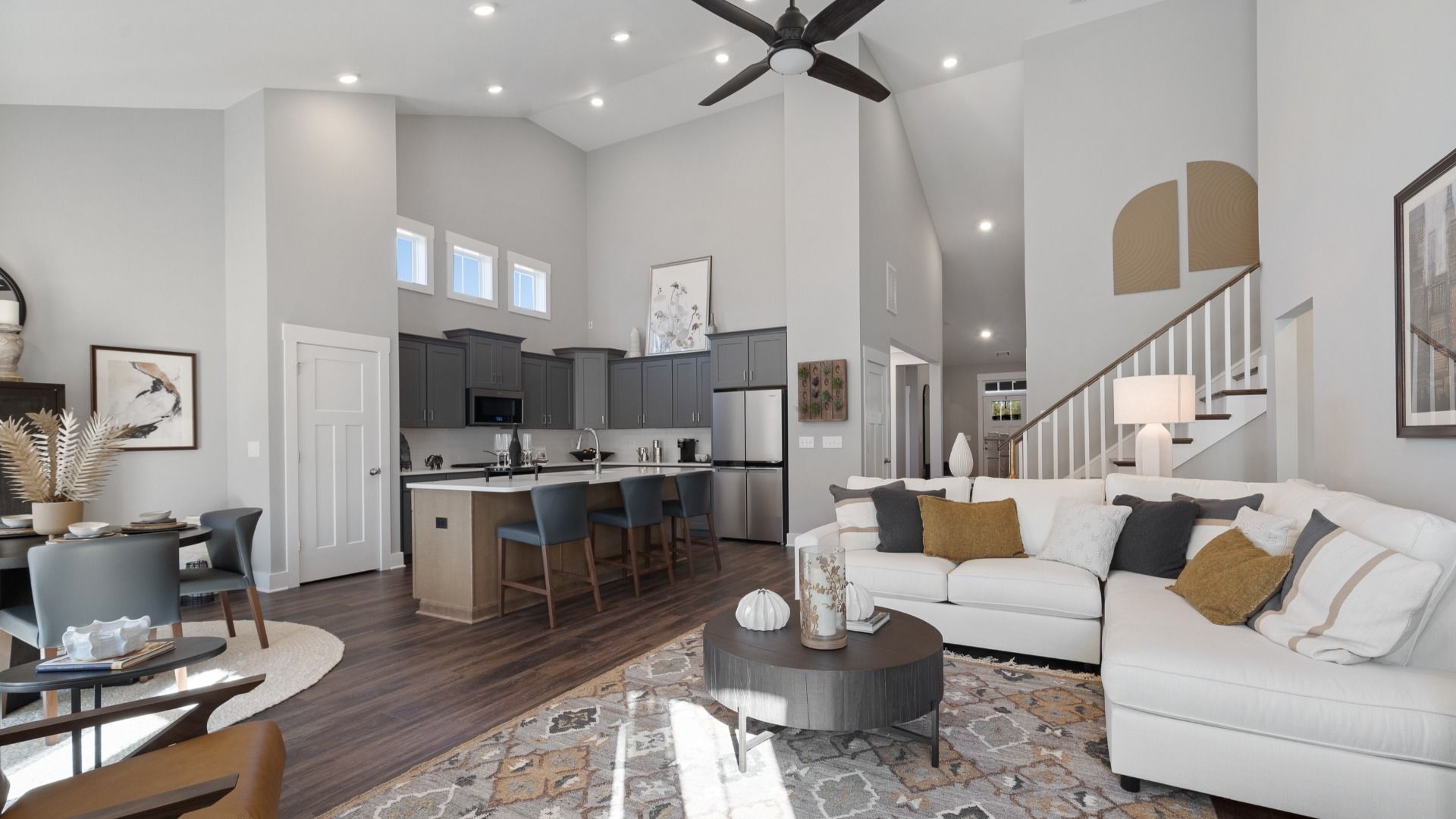 Two story vaulted ceiling family room with hardwood flooring & ceiling fan adjacent from kitchen at Walnut Ridge by DRB Homes