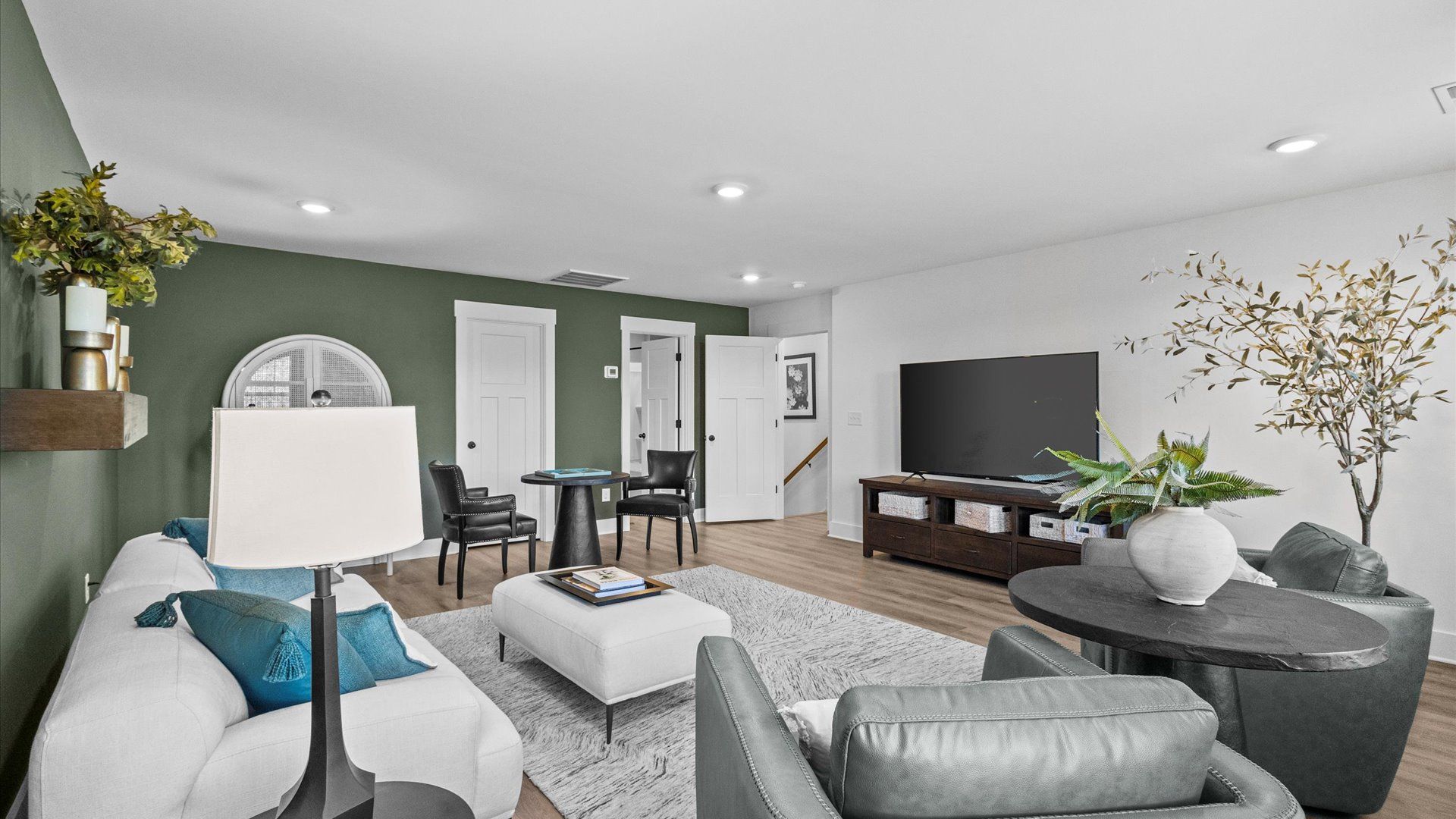 New two-story home with green accent wall, hardwood flooring, and overhead lighting at Wells Crossing by DRB Homes