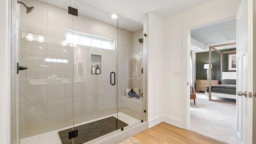Luxury primary bathroom with tiled walk-in Roman shower with bench seat at Fox Hollow by DRB Homes in Spartanburg, SC