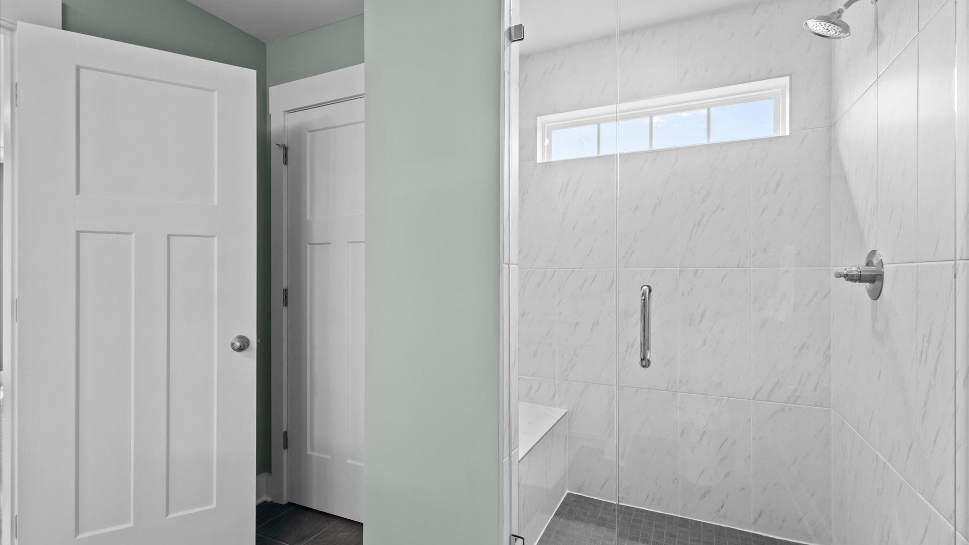 DRB Homes' Woodglen offering a luxe primary bathroom with a stunning marble tiled, frameless walk-in shower with bench seat