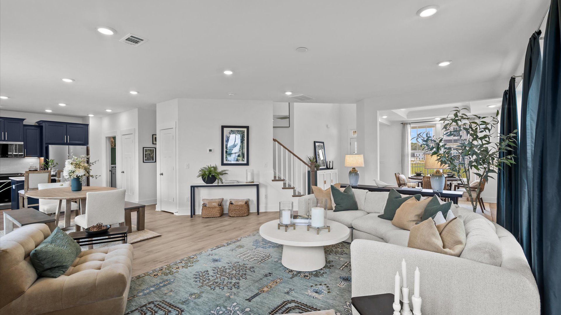 DRB Homes' Woodglen with open concept family room with cozy furniture, hardwood flooring, and large windows