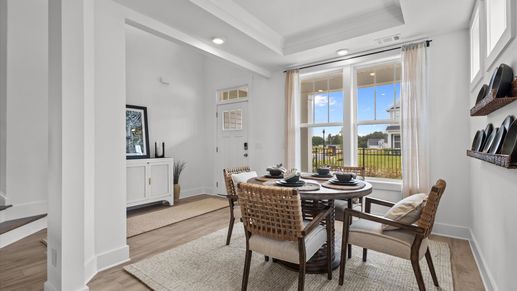 Hardwood flooring dining room with bright white walls and vaulted ceiling at Woodglen by DRB Homes